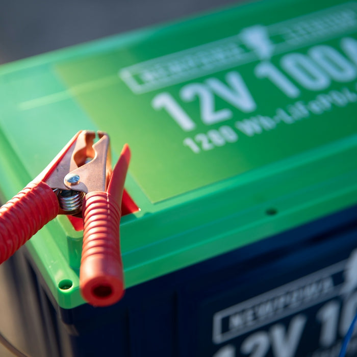a red and green battery with a pair of pliers attached to it