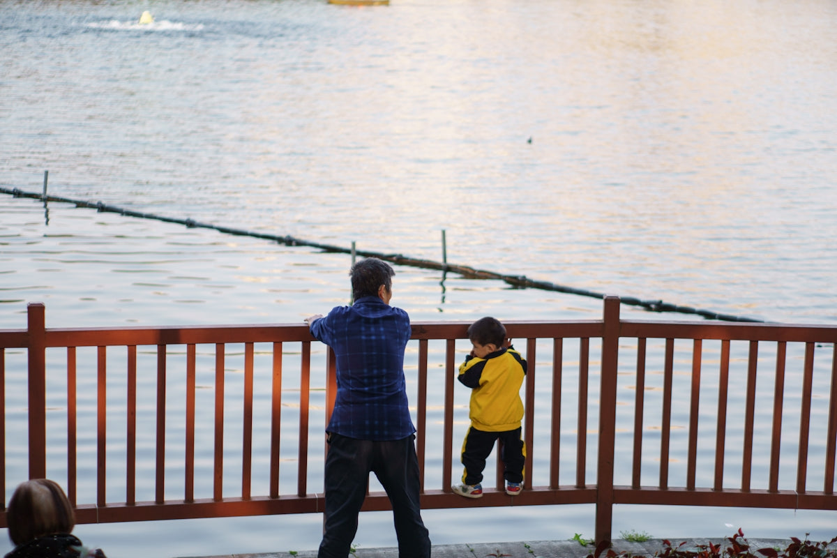 a man standing next to a little boy near a body of water