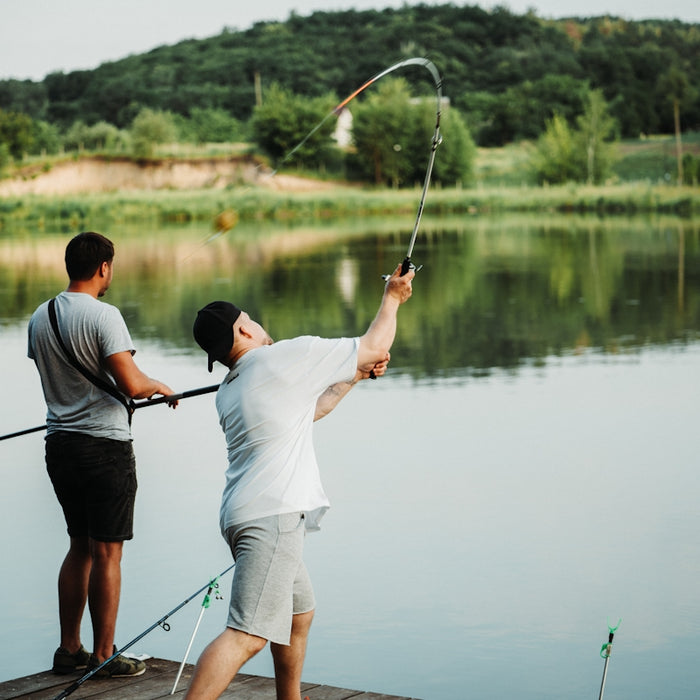 a couple of men standing on top of a pier next to a lake
