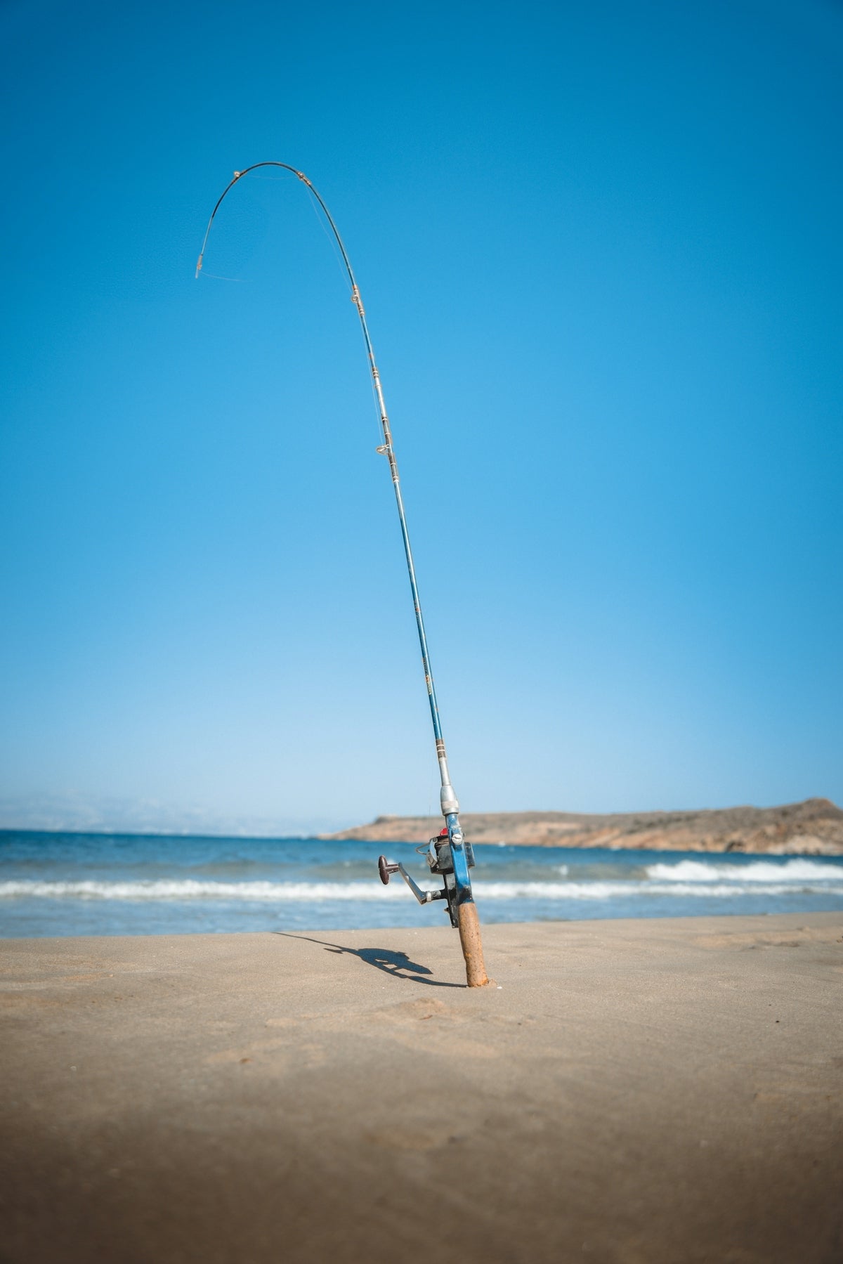 a fishing rod on the beach with a blue sky in the background