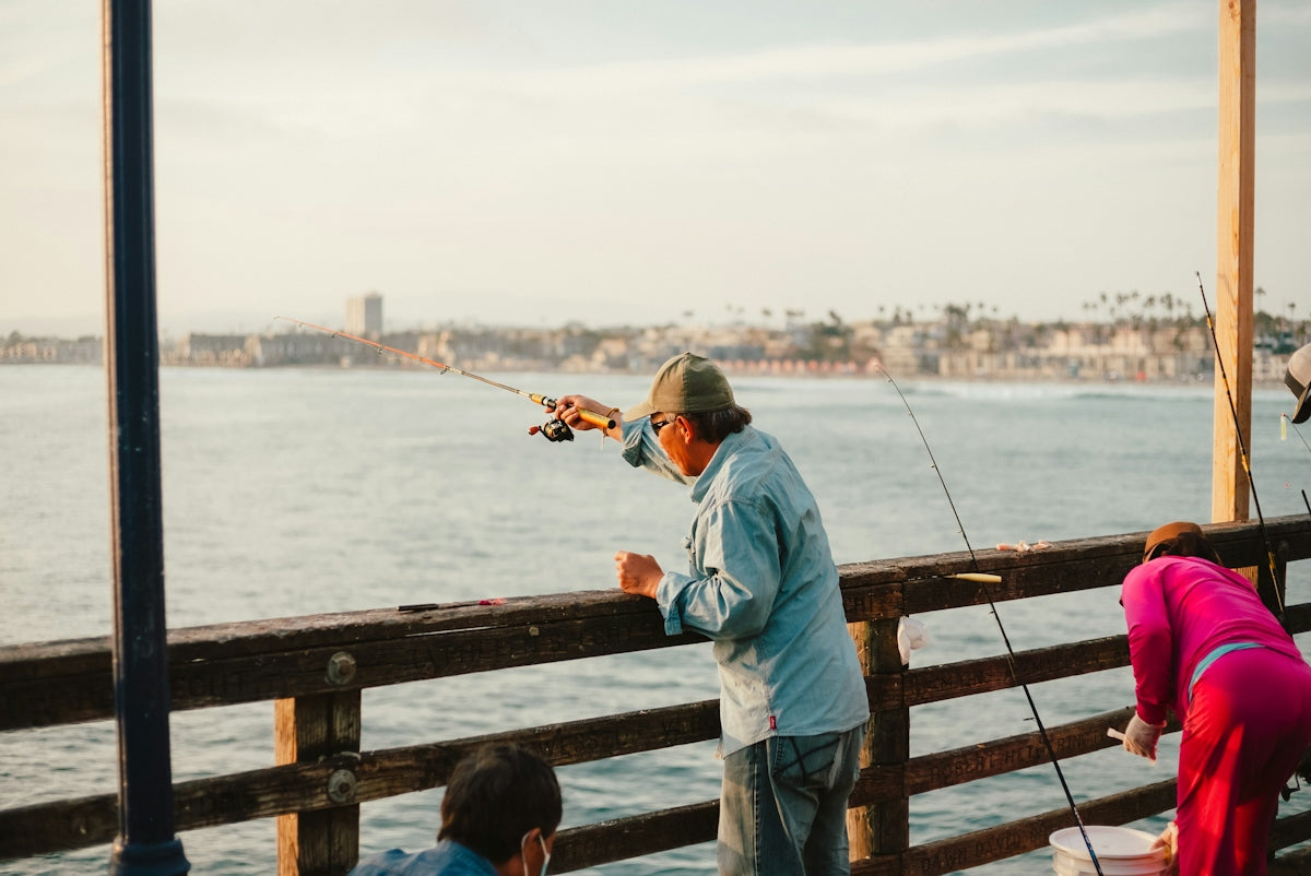 a man standing on a pier holding a fishing rod
