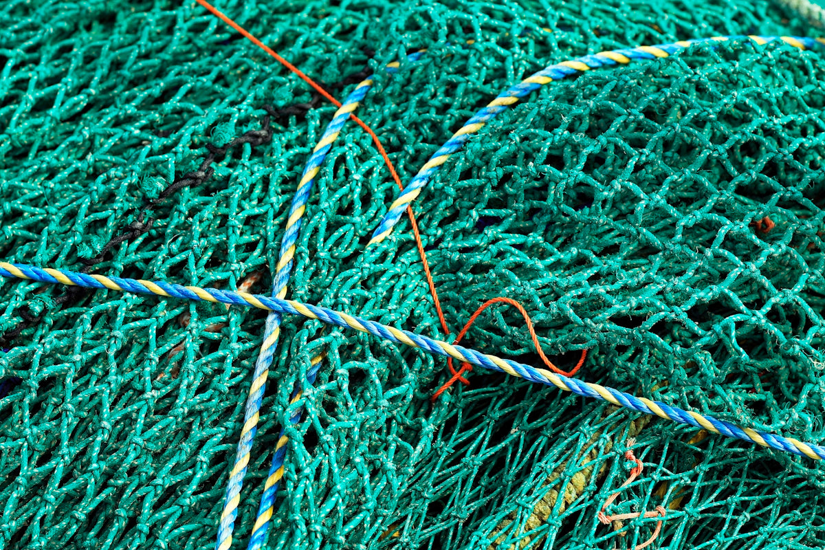 a pile of green fishing nets sitting on top of a beach