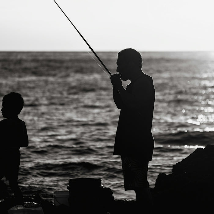 a black and white photo of a man and a child fishing