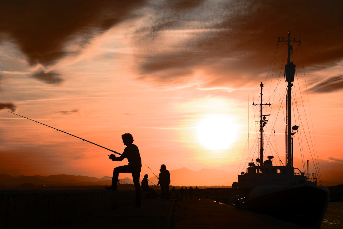 a man standing on a dock while holding a fishing pole