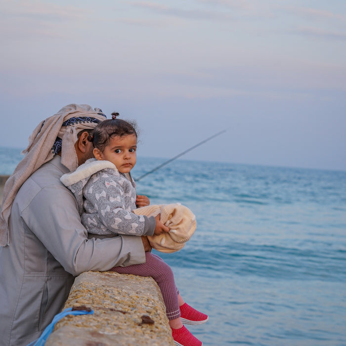 a woman and a child are sitting on a wall by the water