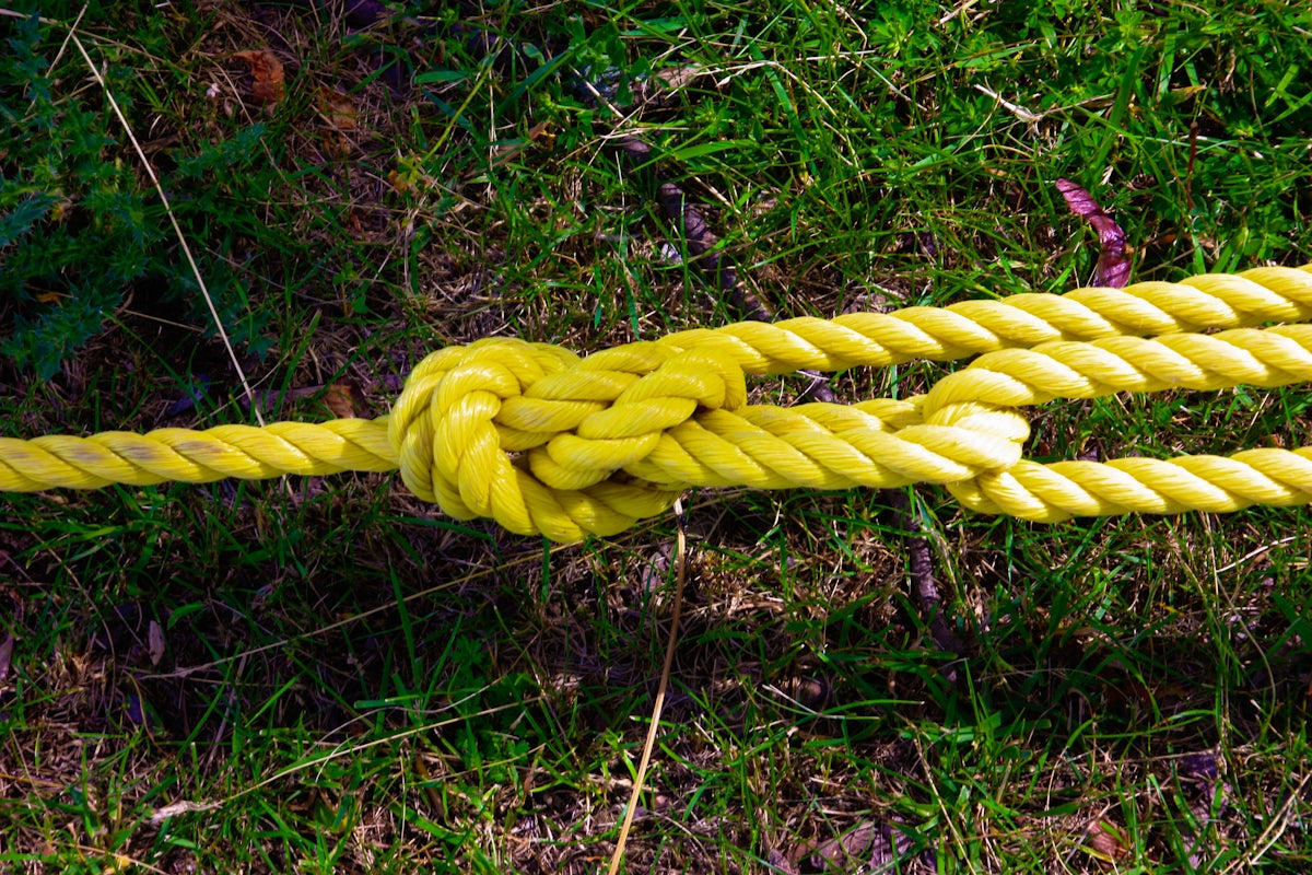 Close-up of a knot in Advantage 20mm Double Braid Rope on grass, showcasing strength and durability.