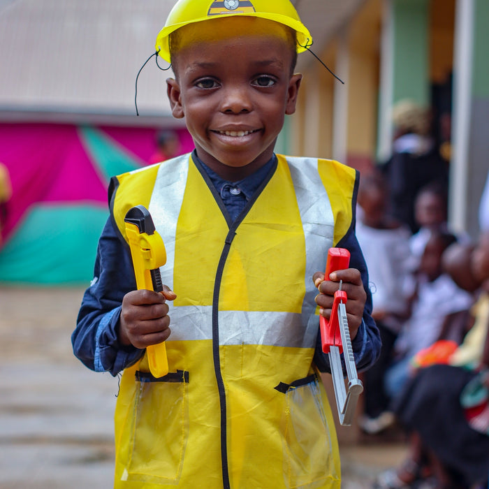 A young boy wearing a safety vest and holding a tool