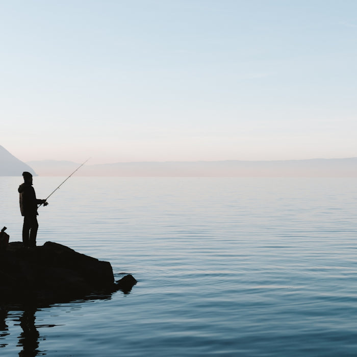 A man standing on a rock in the middle of a body of water