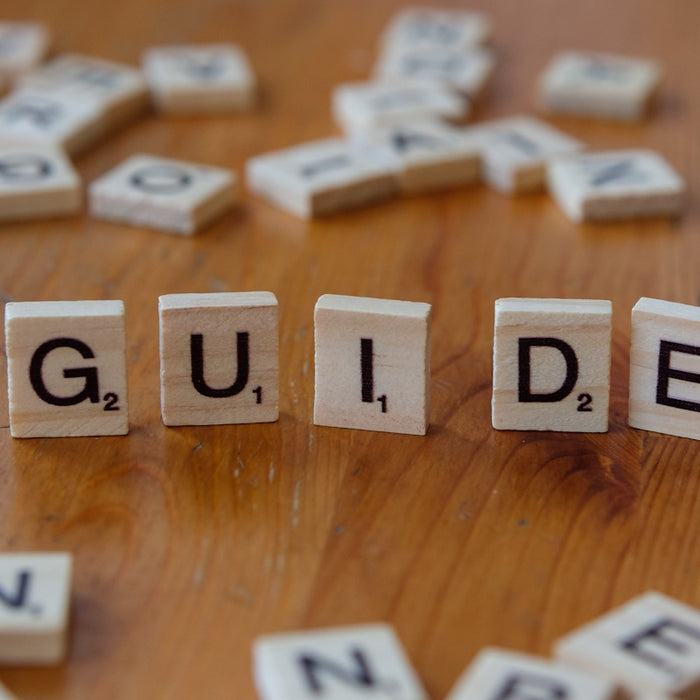 A wooden table topped with scrabble tiles spelling the word guide
