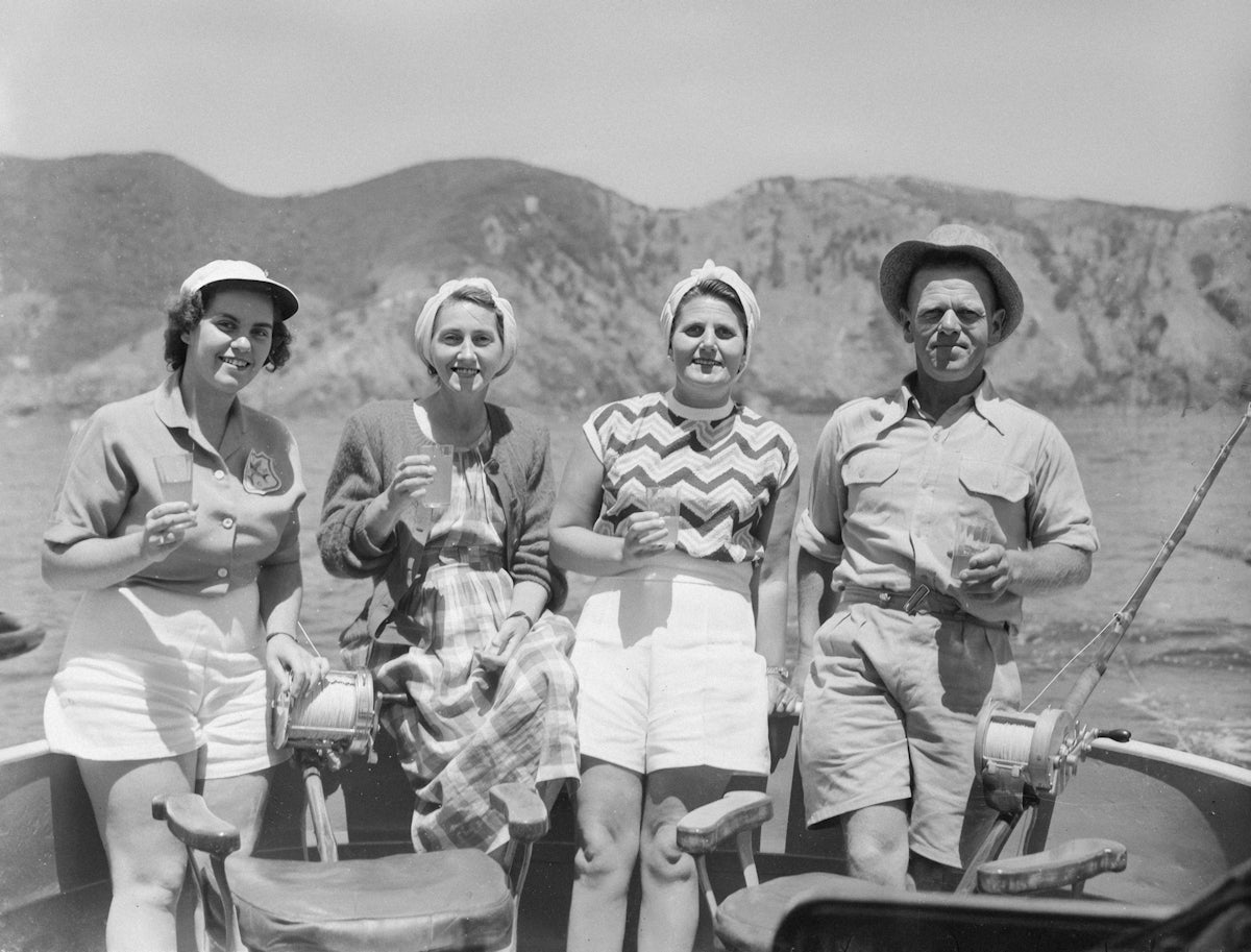 Four people in a boat with hills in background