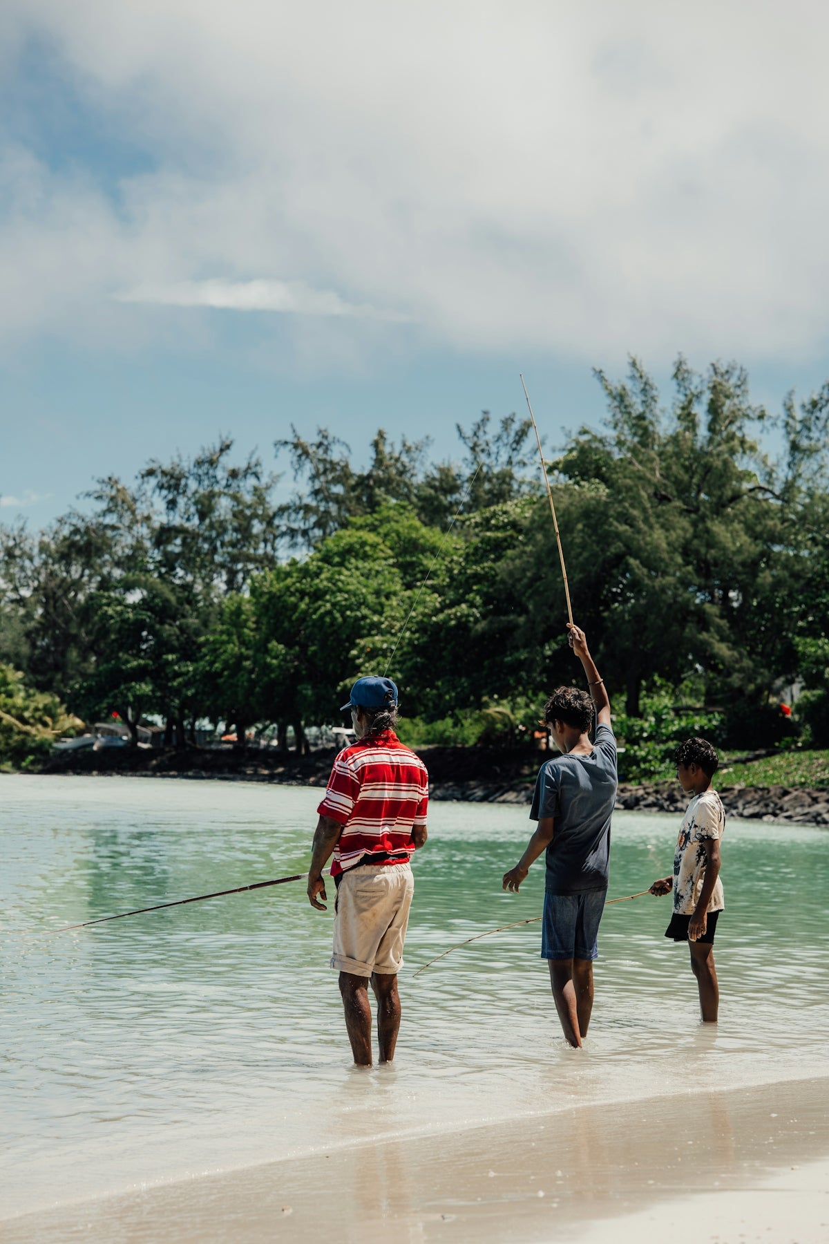Three people are fishing in the shallow water