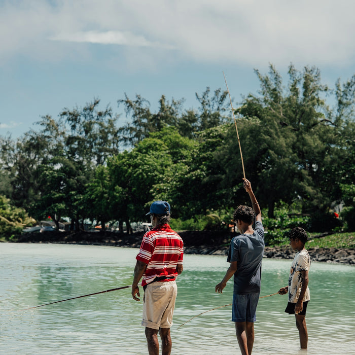 Three people are fishing in the shallow water