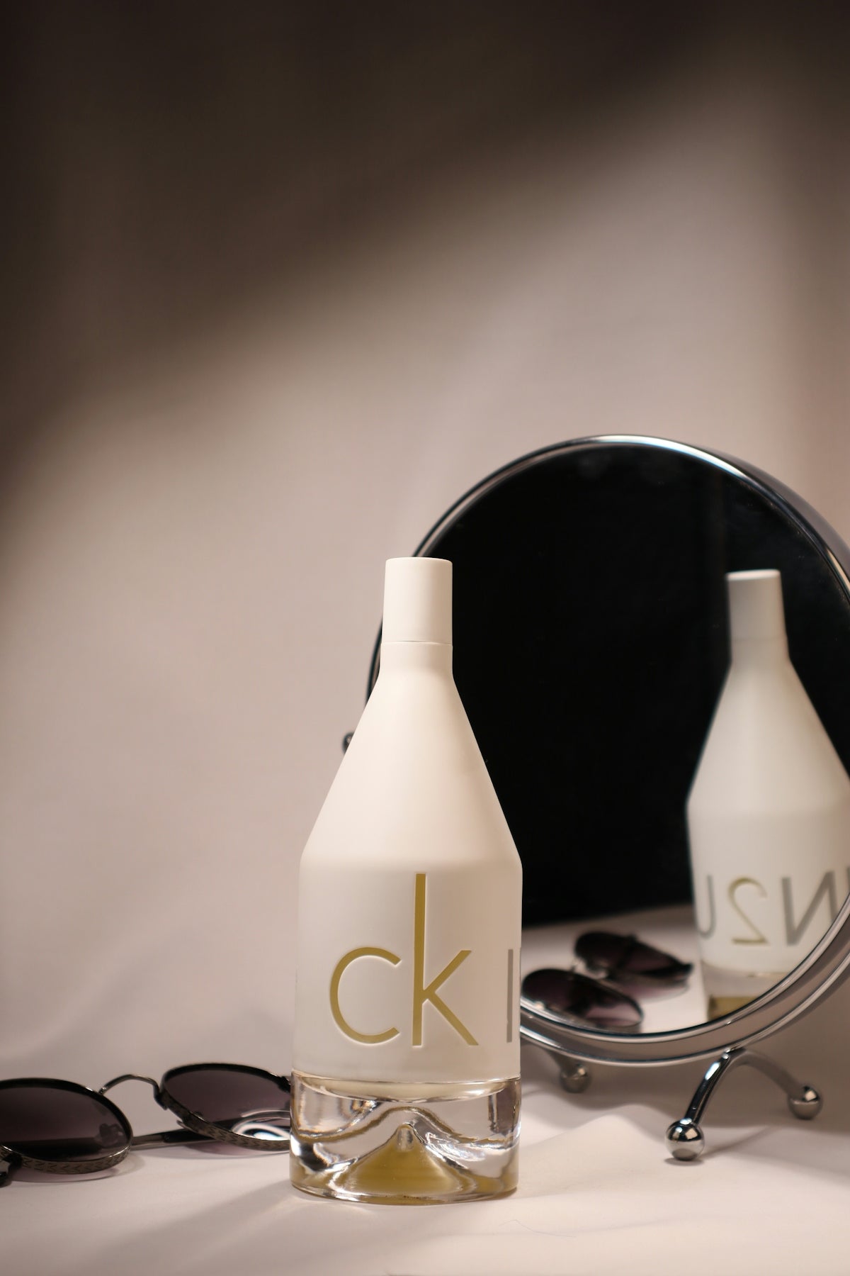 Ck in2u perfume with sunglasses and a mirror.