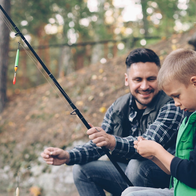 A father and son enjoy fishing together outdoors.