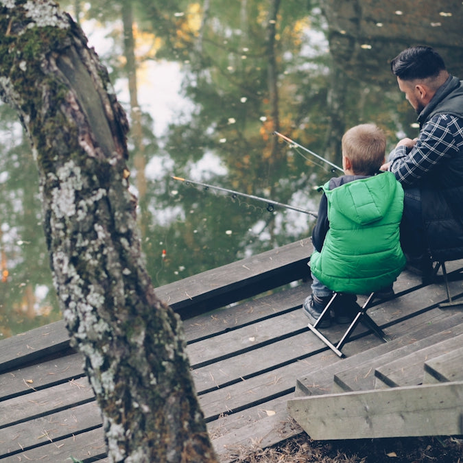 A father and son fishing together by the lake.