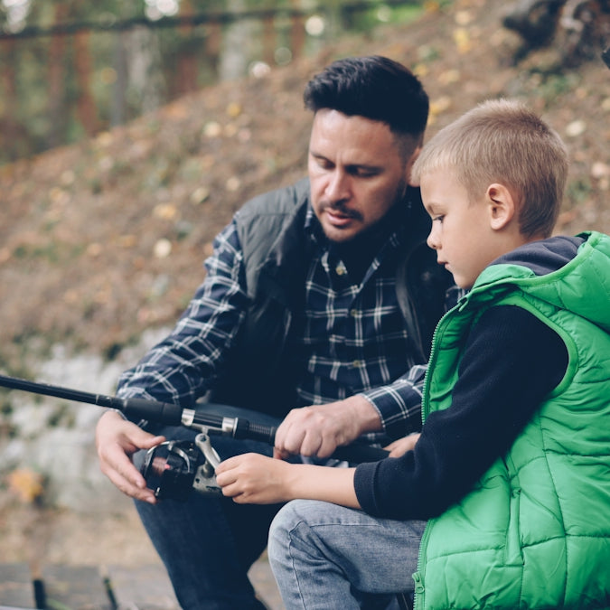 A father shows his son how to fish.
