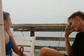 Two people are laughing while sitting on a pier.