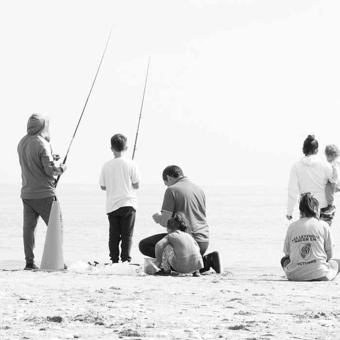 Family fishing together on a sandy beach.