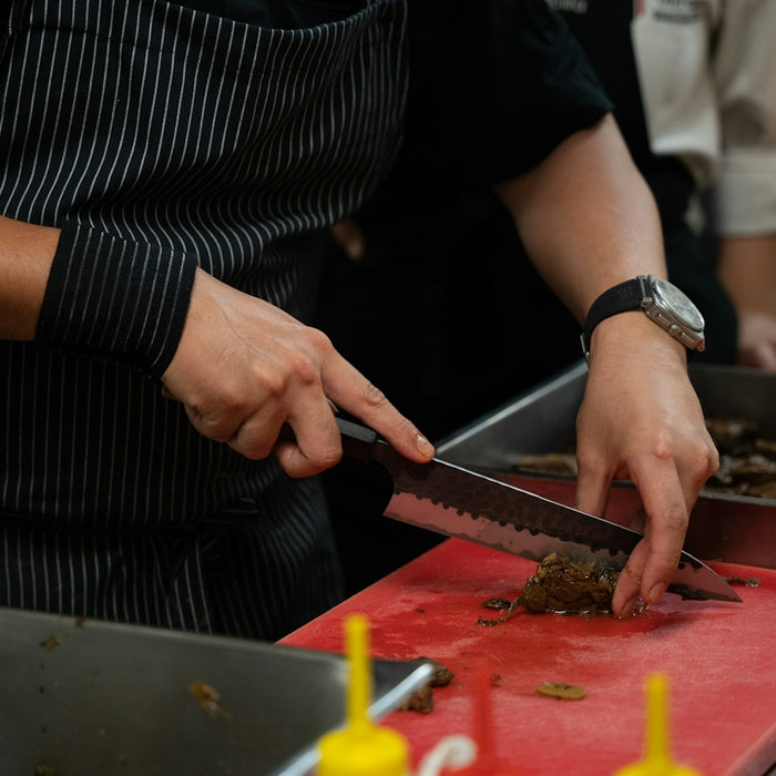 Chef chopping food on a red cutting board