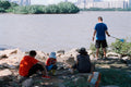 People relaxing by the water with a city skyline.
