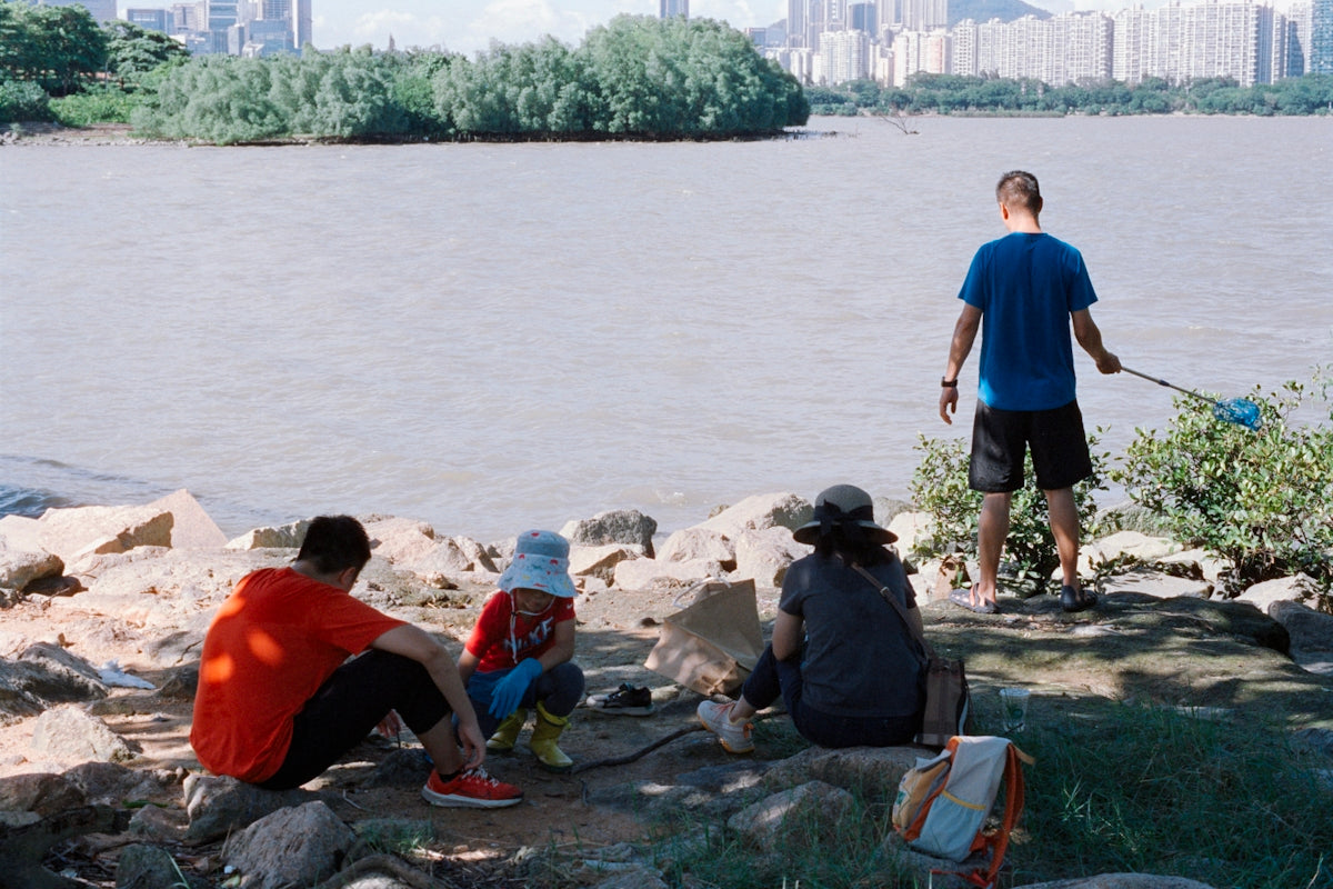 People relaxing by the water with a city skyline.