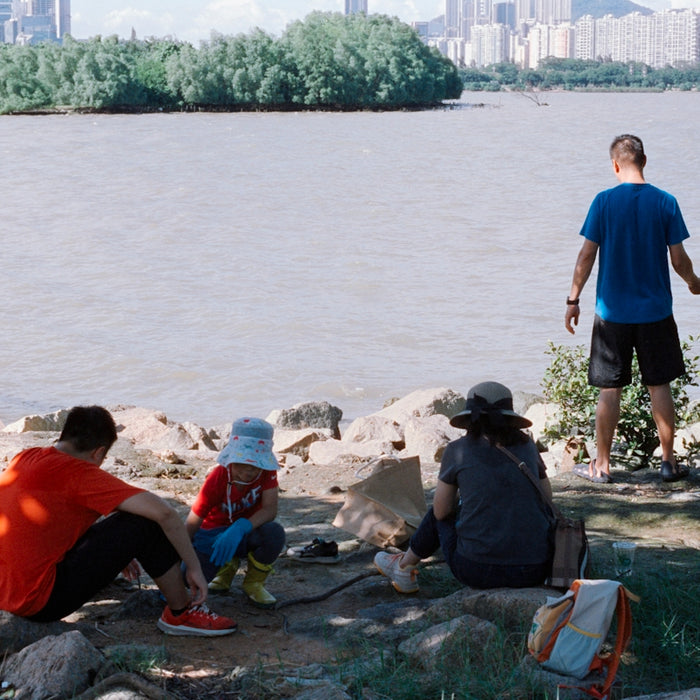 People relaxing by the water with a city skyline.
