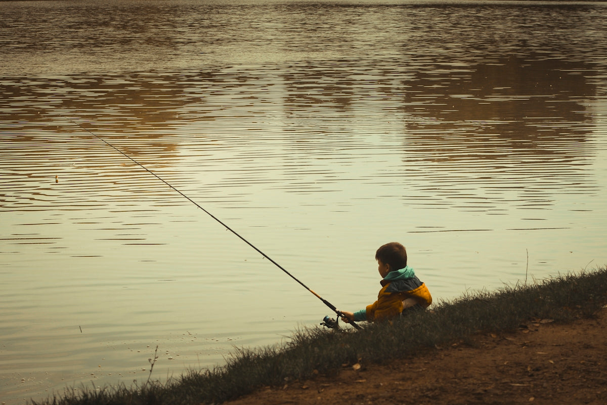 Young boy fishing by the calm lake