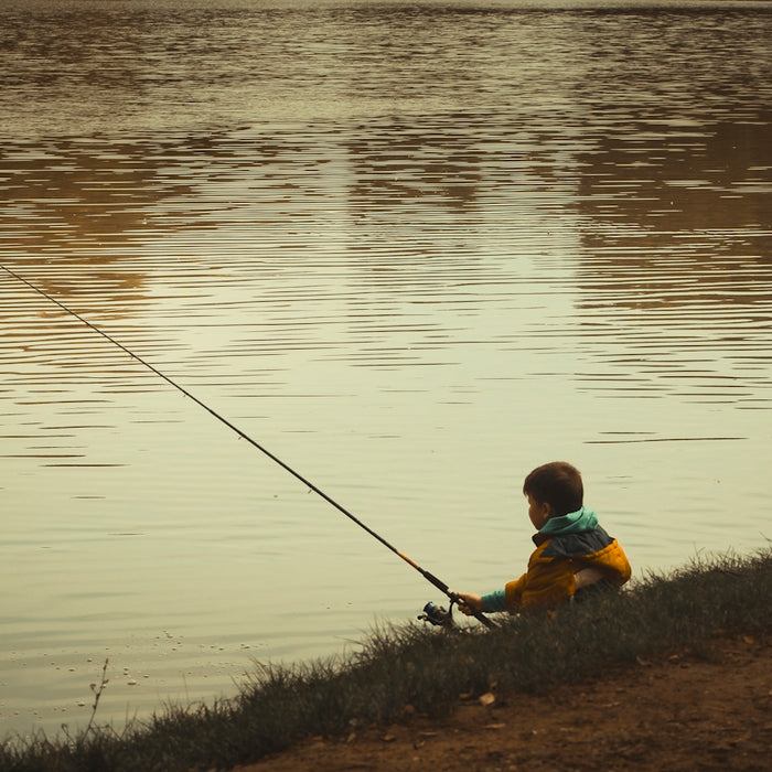 Young boy fishing by the calm lake
