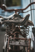 Close-up of a rusty vintage bicycle seat with springs.