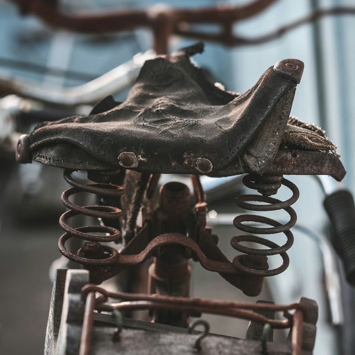 Close-up of a rusty vintage bicycle seat with springs.