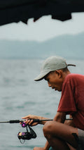 Man wearing a cap fishing from a boat