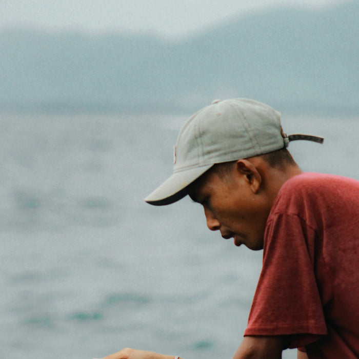 Man wearing a cap fishing from a boat
