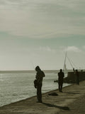 Silhouettes of people fishing on a pier near the ocean