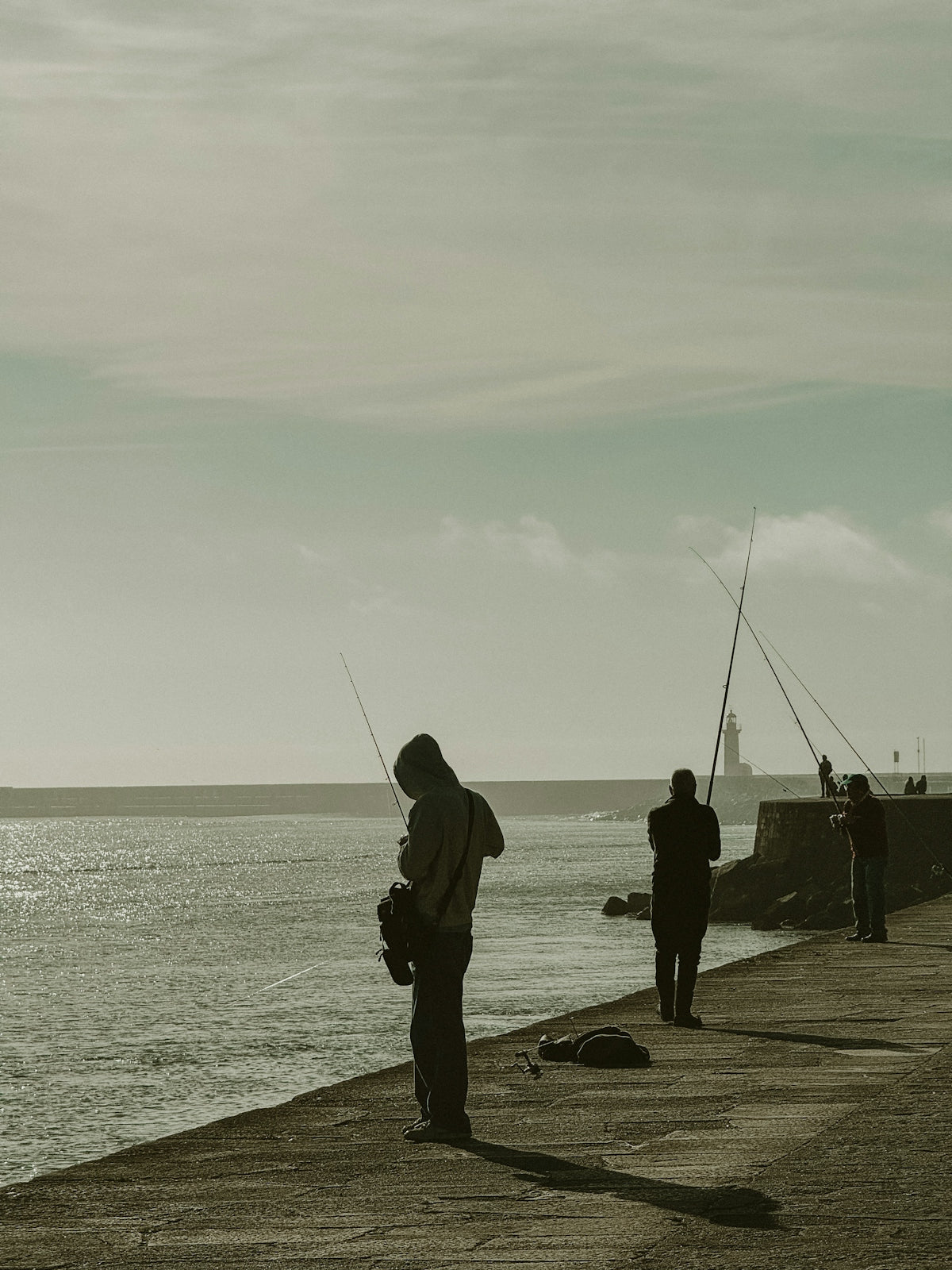 Silhouettes of people fishing on a pier near the ocean