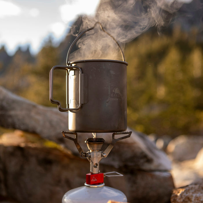 Steam rises from a camping pot on a portable stove.