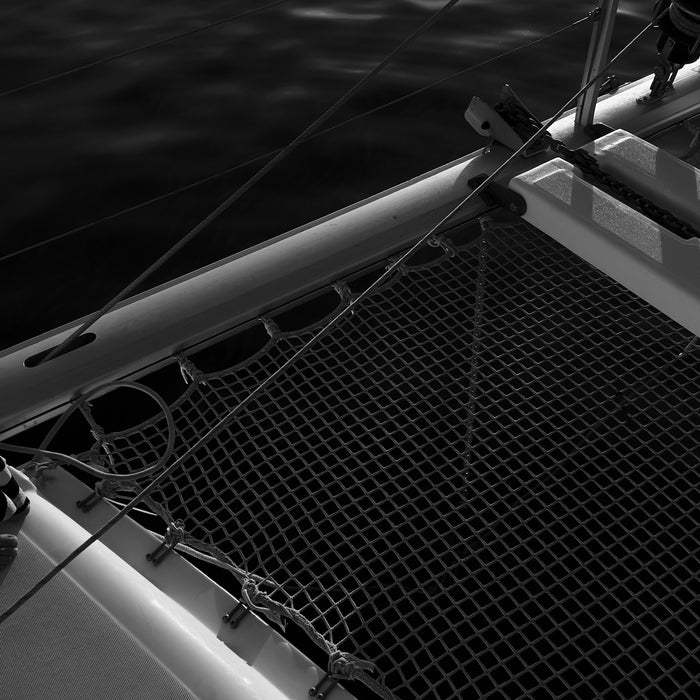 Catamaran bow with netting over sparkling water, black and white
