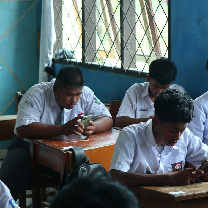 Students in uniform using phones in a classroom