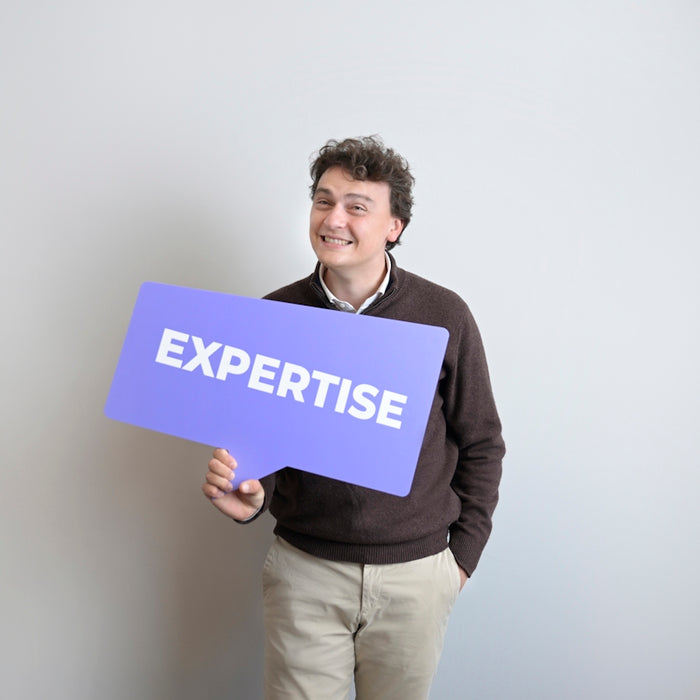 Smiling man holds a purple expertise sign.