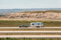 Car towing a silver travel trailer on a highway