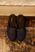 Dark blue crocodile-textured slippers on a polished marble floor