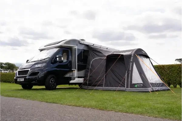 Vango Kela Pro Air Tall Drive Away Awning with Carport and Digital Pump - In Store, set up next to a campervan.