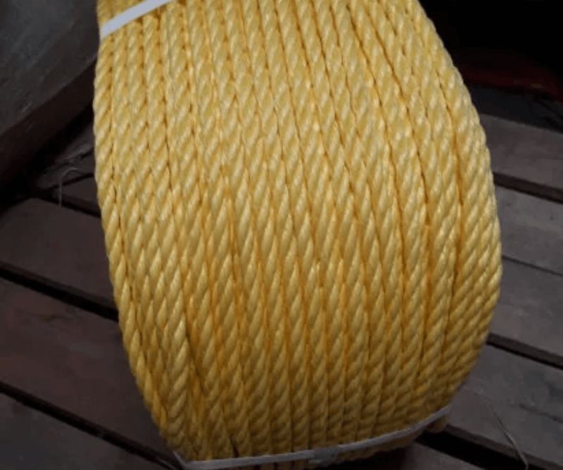 Powerdan 3 strand 220m Rope - A close-up of sturdy yellow rope coiled on a wooden surface.