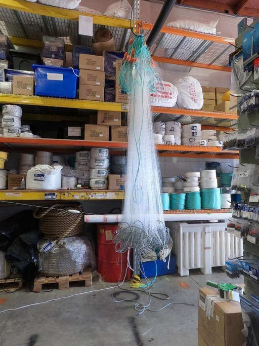 NZ Mullet Fishing Net 60m hanging in a storage area filled with fishing supplies and equipment.