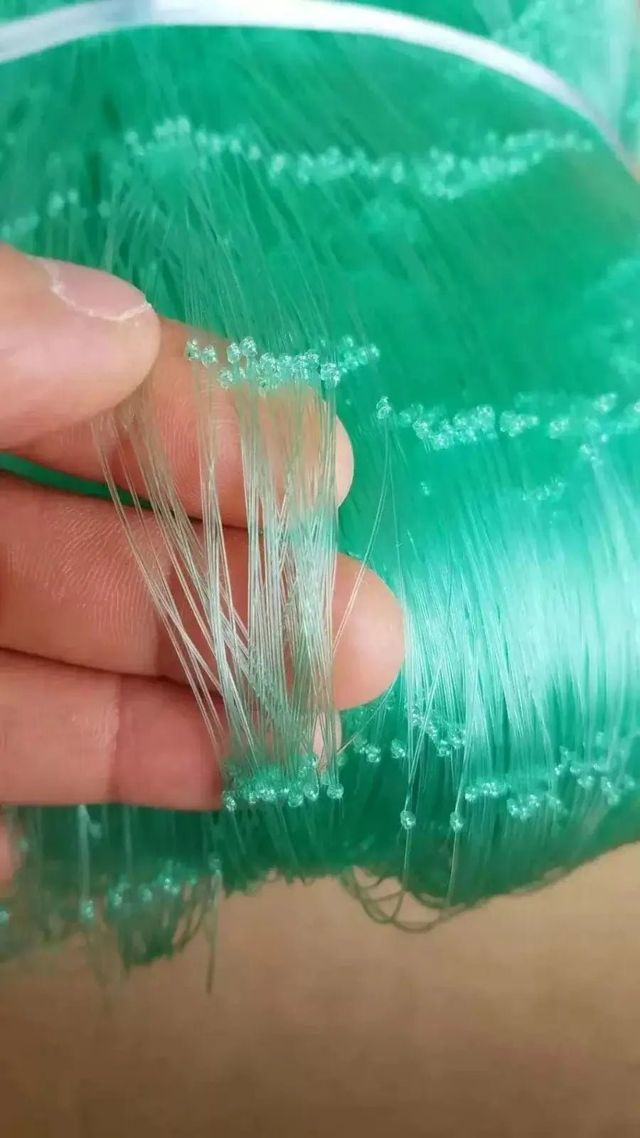 Green Mono Net 0.9mm x 6 1/2 inch x 15MD x 450m strands held by hand, showcasing durability and quality.