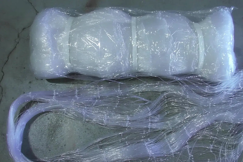 Clear fishing line spool with a green label on a concrete surface