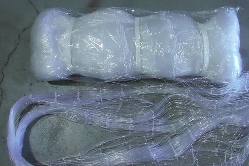 Clear fishing line spool with a green label on a concrete surface