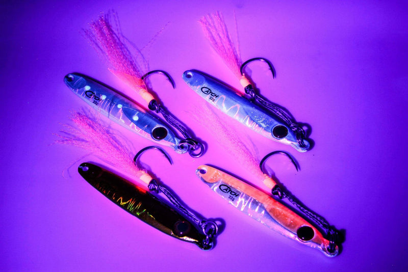 Catch Pocket Rocket Tungsten lures glowing under UV light, showcasing various colors and designs for effective fishing.