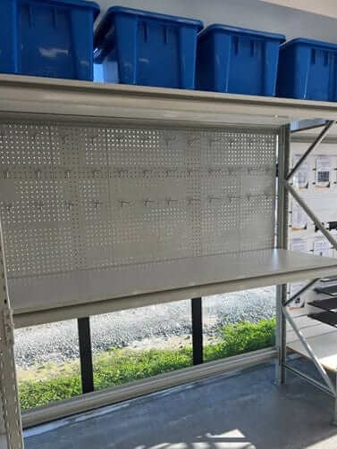Workbench with Pegboard setup featuring metal pegboard, top shelf, and blue storage bins.