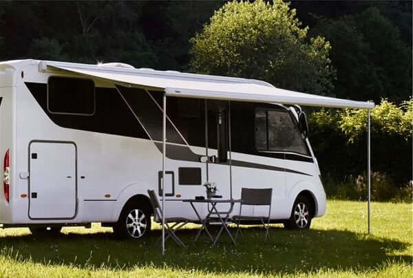 Thule 5200 Awning Sapphire Blue - 4.5m installed on a stylish RV in a lush green outdoor setting.