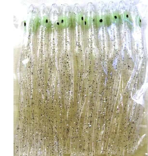 Needle Fish Clear 90 MM PKT10 fishing skirts in clear and green with black spots, enhanced for attracting fish.